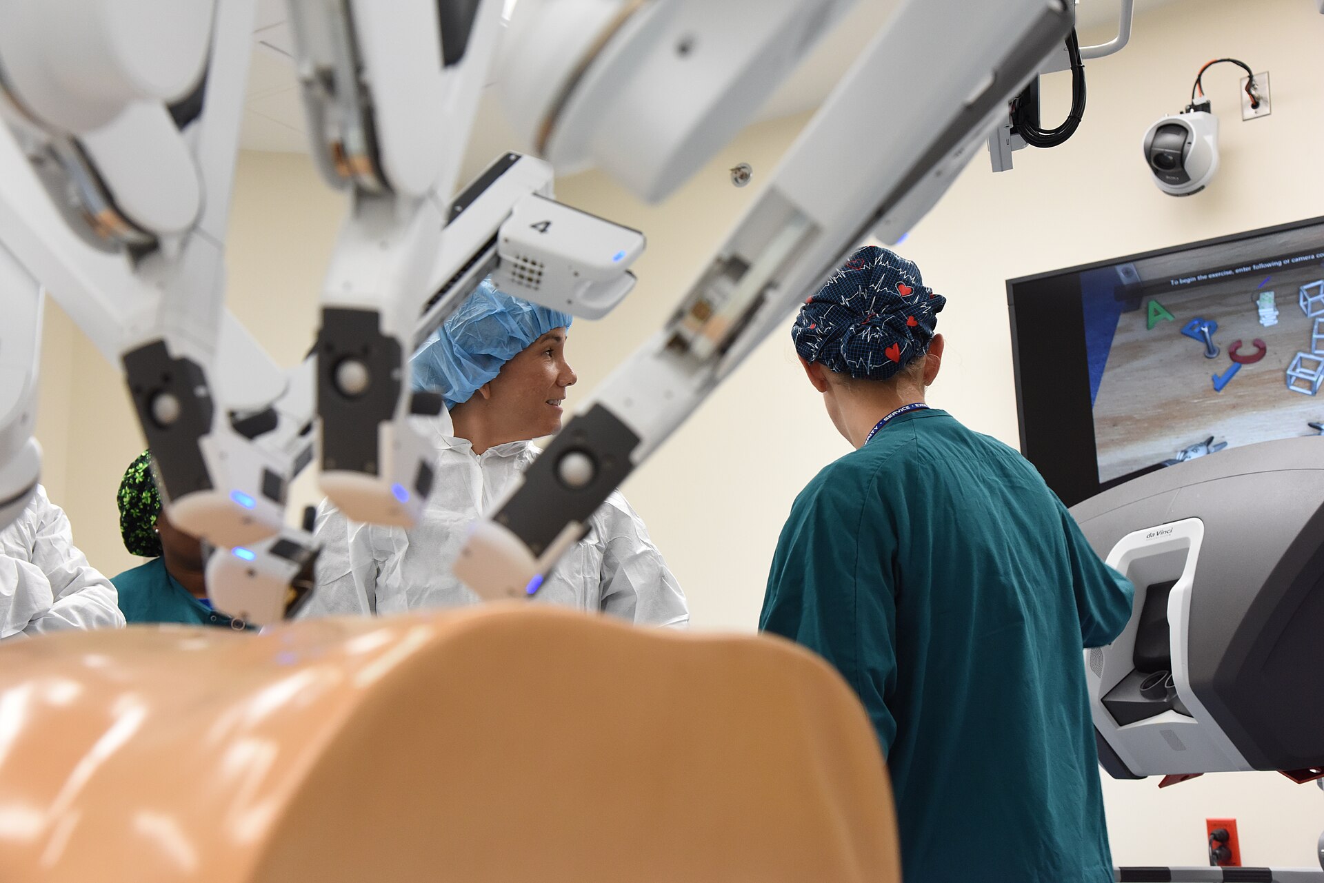 Surgeons at the arms of a surgical robot in an operating room